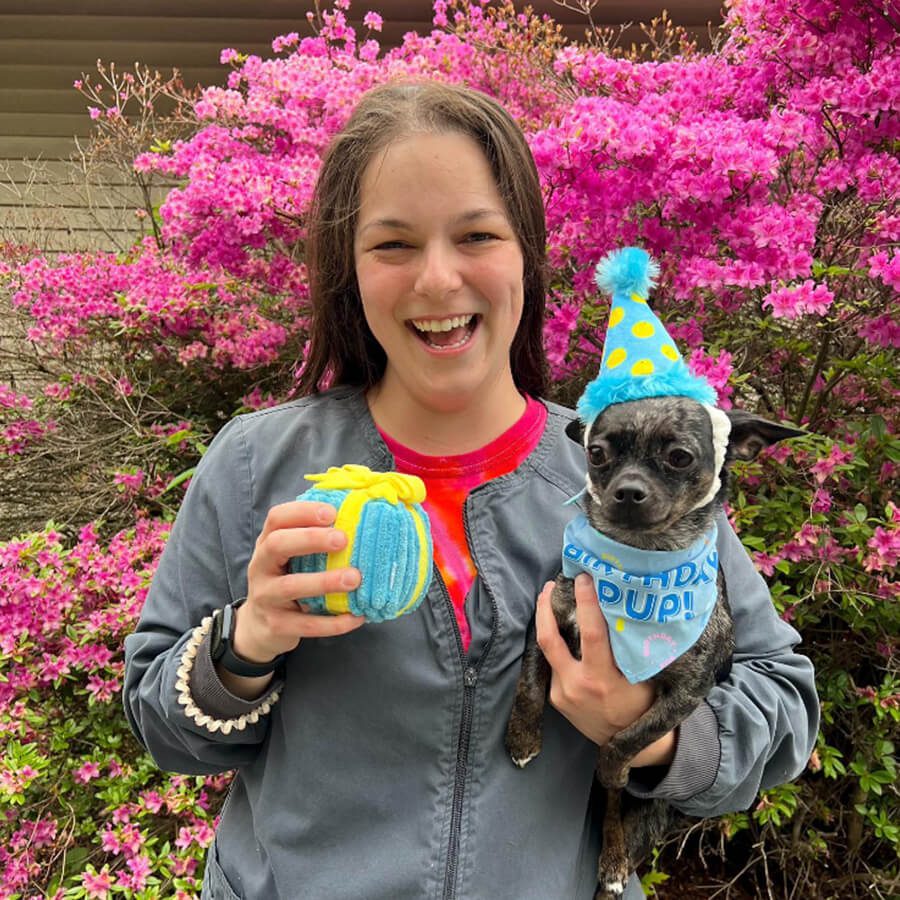 woman holding dog in birthday hat
