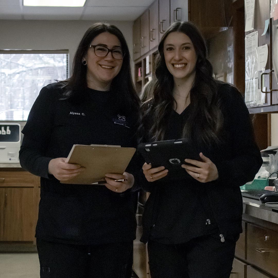 two assistants holding clipboards snd smiling