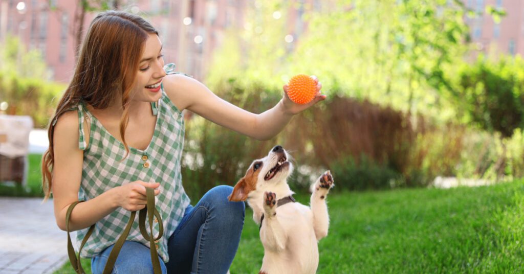 young woman playing with her small dog outside